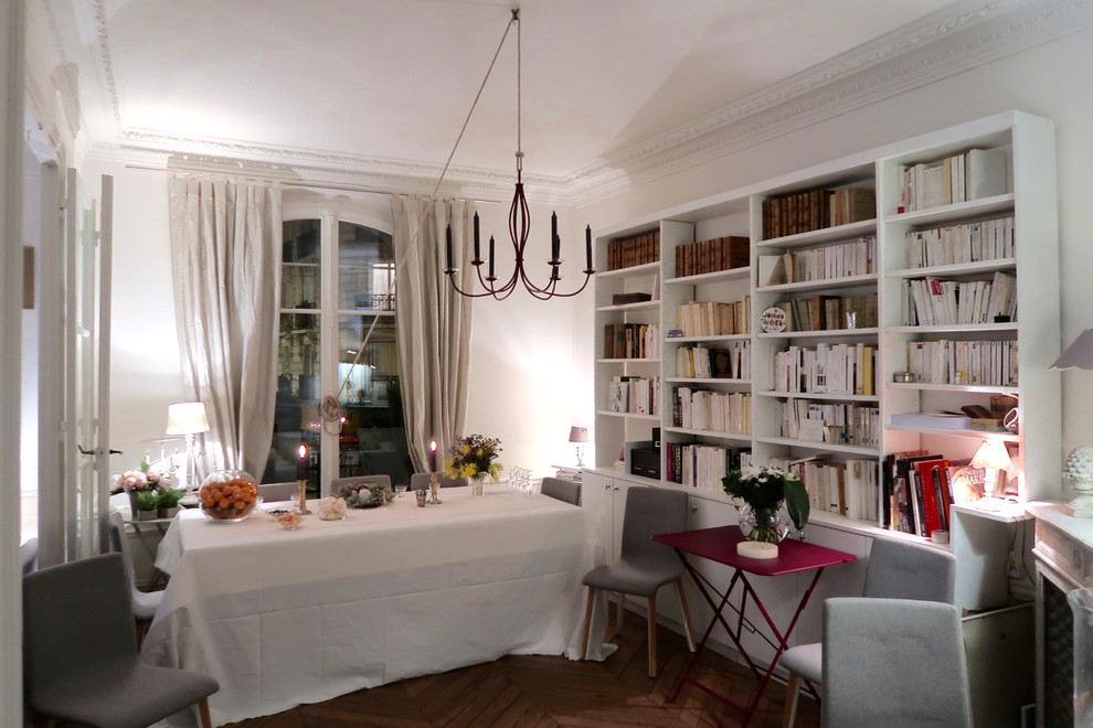 This is an example of a large traditional separate dining room in Paris with white walls, medium hardwood floors, a standard fireplace and brown floor.