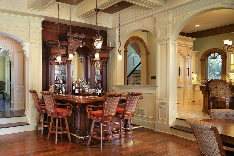 This is an example of a traditional u-shaped seated home bar in New York with wood benchtops, mirror splashback, dark hardwood floors and brown benchtop.