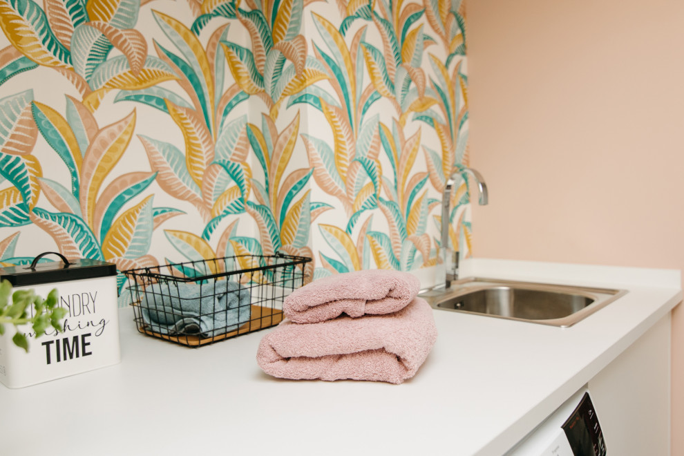 Foto de lavadero actual pequeño con puertas de armario blancas, encimera de madera, paredes rosas, lavadora y secadora juntas, encimeras blancas y papel pintado