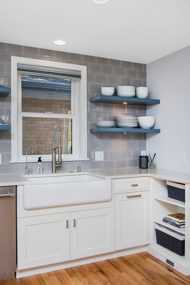 Large transitional u-shaped light wood floor enclosed kitchen photo in Denver with a farmhouse sink, shaker cabinets, white cabinets, quartz countertops, gray backsplash, ceramic backsplash, stainless steel appliances and an island