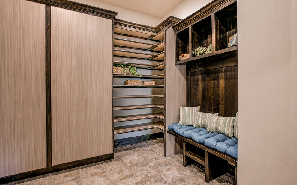 This is an example of a large transitional mudroom in Denver with beige walls, travertine floors, a single front door and a dark wood front door.