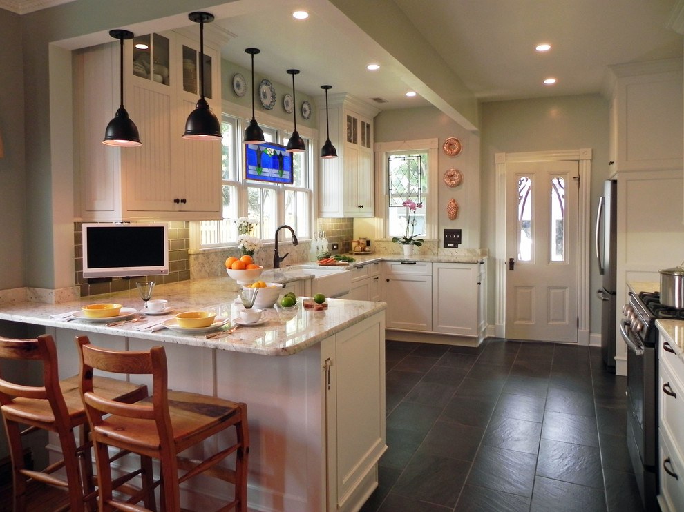 Mid-sized traditional u-shaped eat-in kitchen in Baltimore with a farmhouse sink, shaker cabinets, white cabinets, marble benchtops, grey splashback, subway tile splashback, stainless steel appliances, slate floors, a peninsula and grey floor.