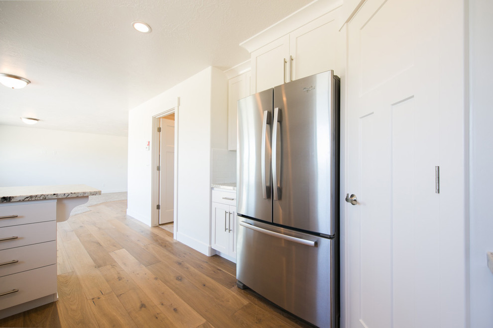 This is an example of a large arts and crafts eat-in kitchen in Salt Lake City with granite benchtops, white splashback, subway tile splashback, stainless steel appliances and light hardwood floors.