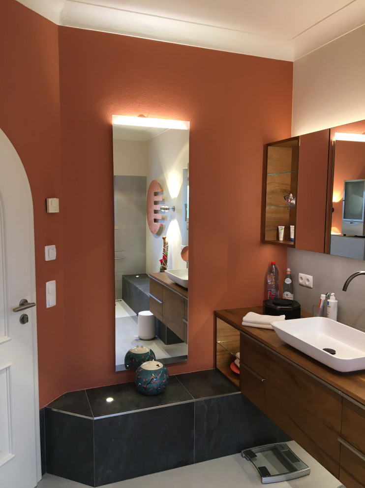 Exempel på ett stort brun brunt en-suite badrum, med skåp i mörkt trä, en öppen dusch, en bidé, grå kakel, keramikplattor, röda väggar, klinkergolv i keramik, ett fristående handfat, träbänkskiva, grått golv och med dusch som är öppen