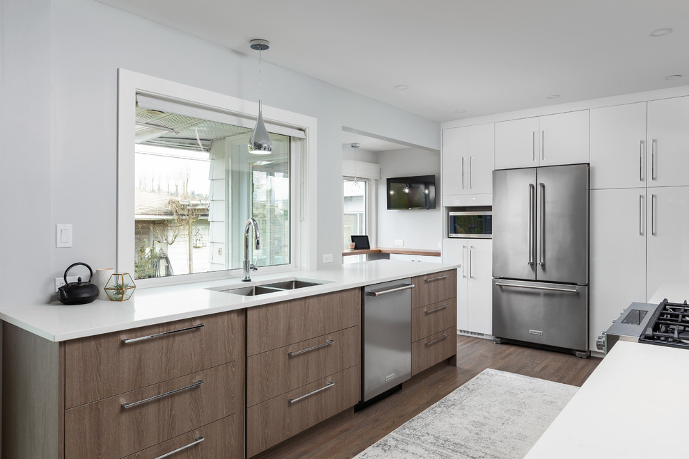 Inspiration for a mid-sized contemporary galley eat-in kitchen in Vancouver with a double-bowl sink, flat-panel cabinets, white cabinets, quartz benchtops, grey splashback, glass sheet splashback, stainless steel appliances, light hardwood floors, a peninsula, grey floor and white benchtop.
