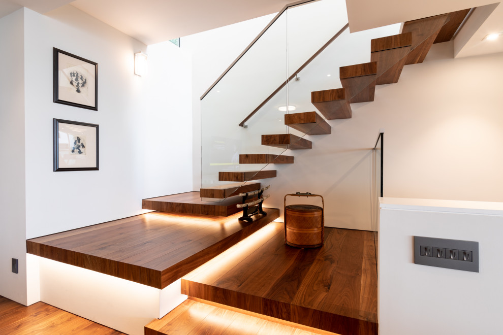 Источник вдохновения для домашнего уюта: большая лестница на больцах в стиле модернизм с деревянными ступенями и стеклянными перилами без подступенок