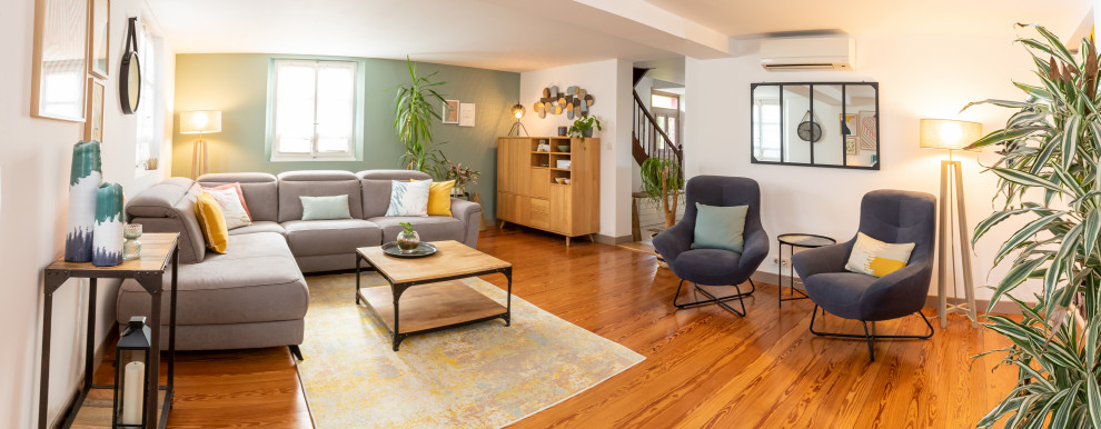 Cette image montre une grande salle de séjour urbaine avec un mur vert et un sol en bois brun.
