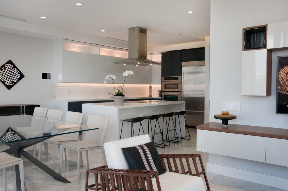Design ideas for a large modern l-shaped eat-in kitchen in Miami with an undermount sink, glass-front cabinets, grey cabinets, quartzite benchtops, white splashback, slate splashback, stainless steel appliances, marble floors, with island and white floor.