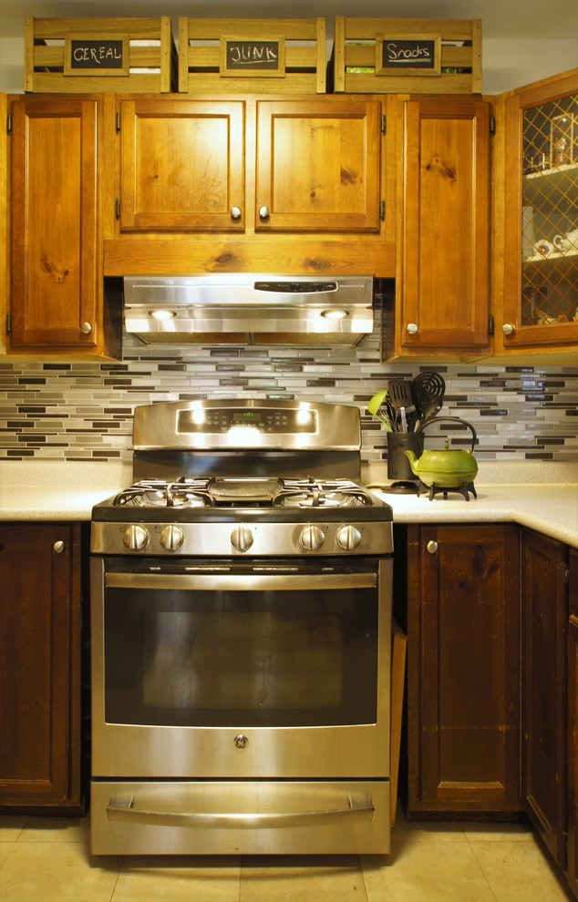 Example of a mid-sized transitional u-shaped vinyl floor eat-in kitchen design in Toronto with a double-bowl sink, shaker cabinets, medium tone wood cabinets, laminate countertops, multicolored backsplash, mosaic tile backsplash, stainless steel appliances and a peninsula