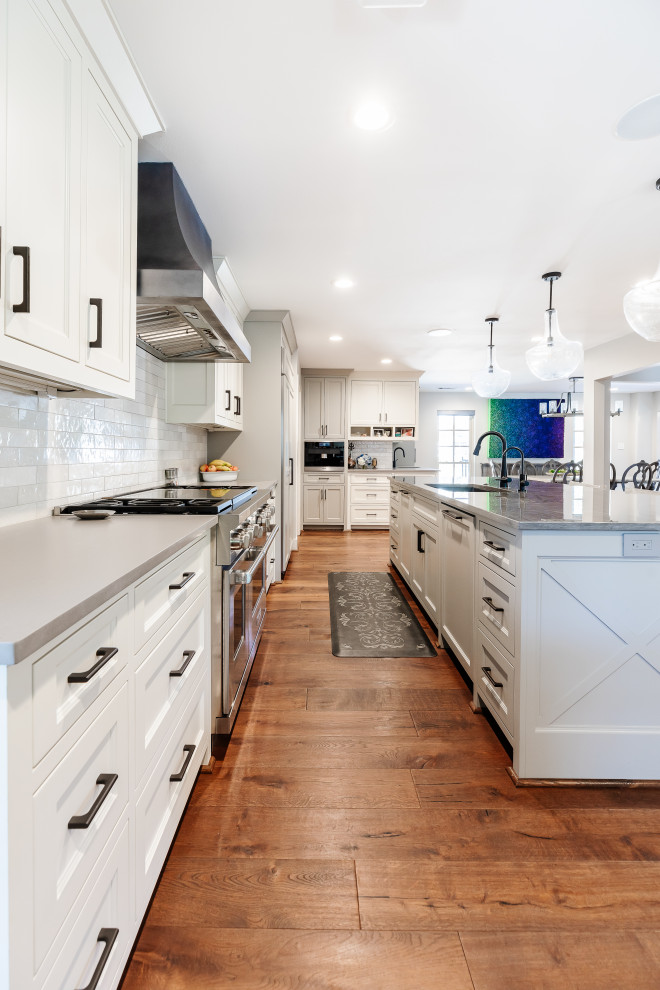 Design ideas for a large transitional open plan kitchen in Dallas with an undermount sink, flat-panel cabinets, grey cabinets, quartz benchtops, white splashback, panelled appliances, medium hardwood floors, with island, brown floor and grey benchtop.