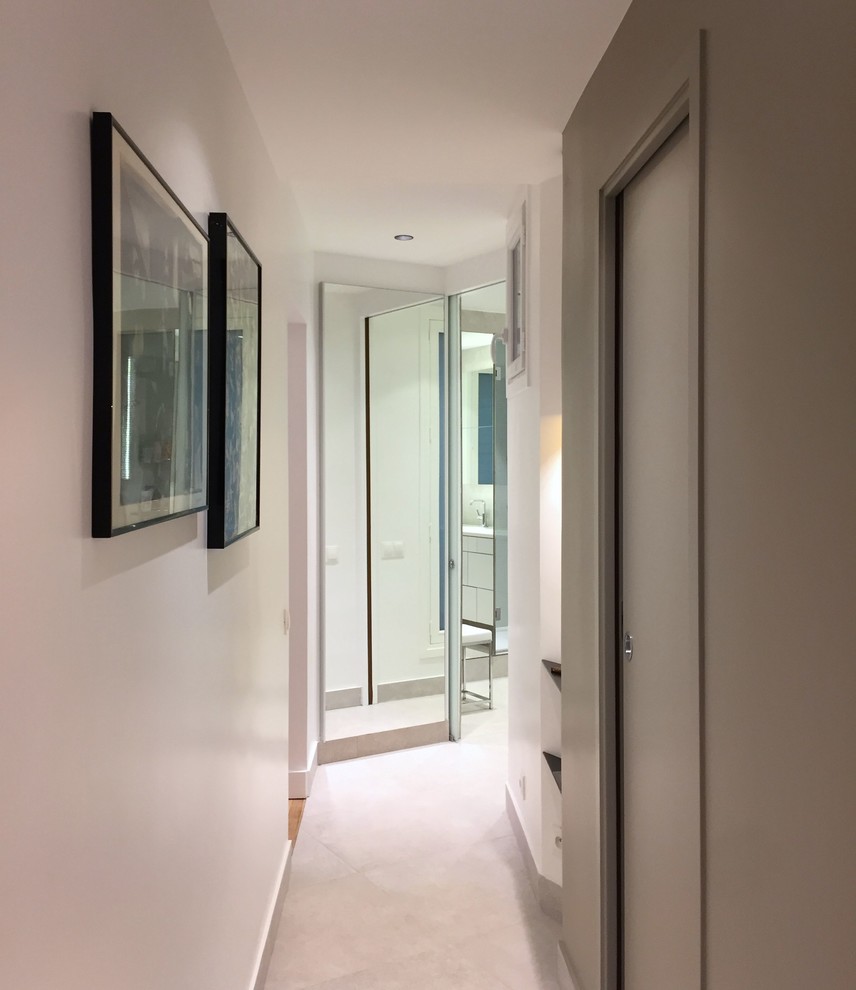 Exemple d'un couloir tendance de taille moyenne avec un sol en carrelage de céramique, un mur blanc et un sol gris.
