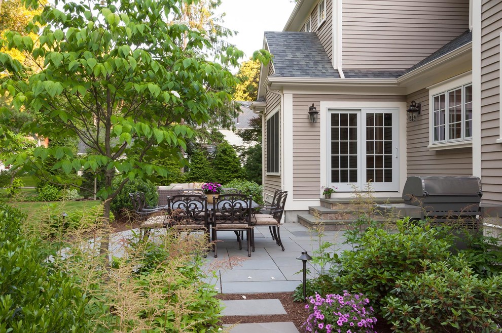 This is an example of a traditional backyard patio in Boston with natural stone pavers.