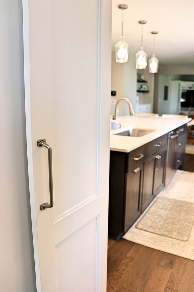 Kitchen pantry - transitional l-shaped medium tone wood floor and brown floor kitchen pantry idea in Cedar Rapids with an undermount sink, recessed-panel cabinets, white cabinets, quartzite countertops, gray backsplash, porcelain backsplash, stainless steel appliances, an island and white countertops