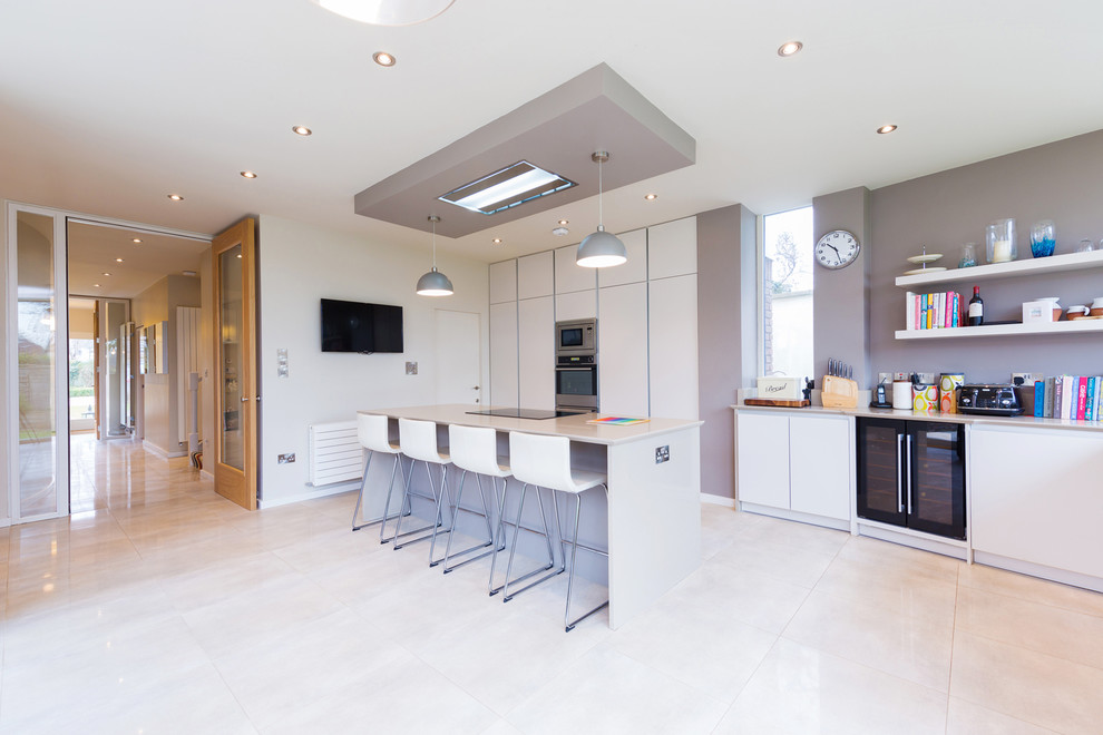 Inspiration for a large contemporary l-shaped open plan kitchen in Dublin with a double-bowl sink, flat-panel cabinets, beige cabinets, quartzite benchtops, beige splashback, stainless steel appliances, ceramic floors and with island.