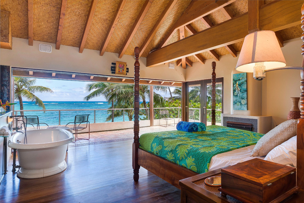 Photo of a tropical master bedroom in Hawaii with beige walls and medium hardwood floors.