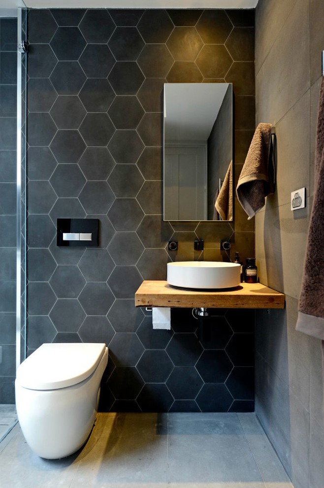 Inspiration for a contemporary bathroom in Kansas City with a vessel sink, wooden worktops, black tiles and concrete flooring.