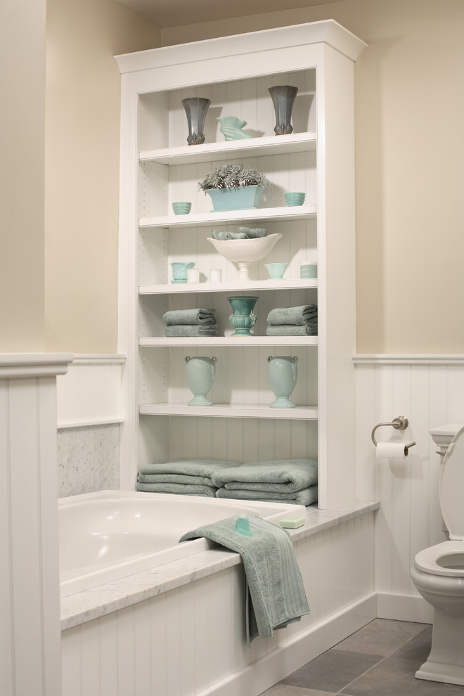 This is an example of a mid-sized traditional bathroom in Chicago with open cabinets, white cabinets, a drop-in tub, a two-piece toilet, gray tile and beige walls.