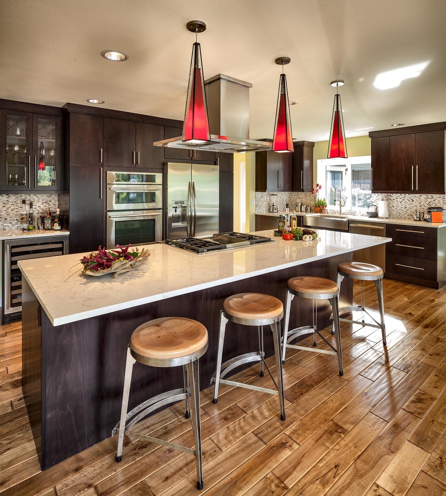 This is an example of a mid-sized contemporary l-shaped eat-in kitchen in Seattle with flat-panel cabinets, dark wood cabinets, multi-coloured splashback, stainless steel appliances, a farmhouse sink, stone tile splashback, medium hardwood floors, with island, quartzite benchtops and brown floor.