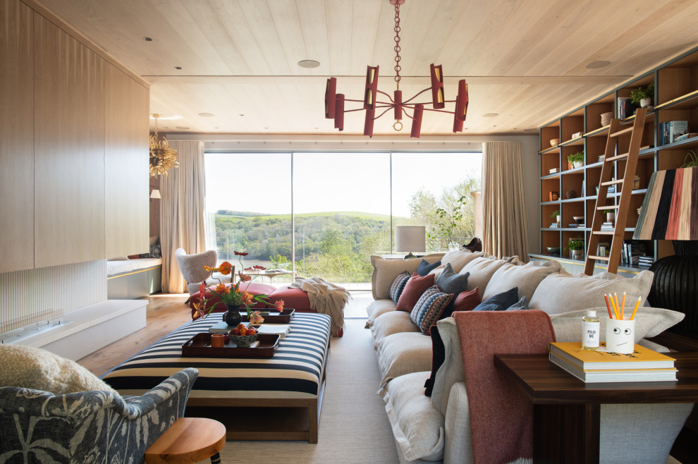 Photo of an expansive contemporary open plan living room in Cornwall with medium hardwood flooring, a stone fireplace surround, a concealed tv and a timber clad ceiling.