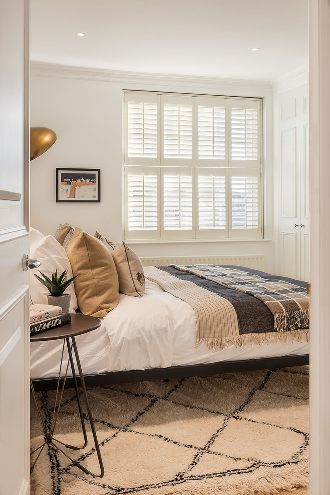 Mid-sized contemporary guest bedroom in Essex with white walls, medium hardwood floors and brown floor.