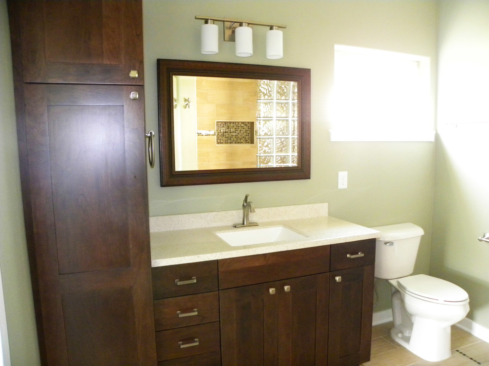 Inspiration for a master bathroom in Cedar Rapids with recessed-panel cabinets, dark wood cabinets, a curbless shower, beige tile, ceramic tile, green walls, ceramic floors, an integrated sink and solid surface benchtops.