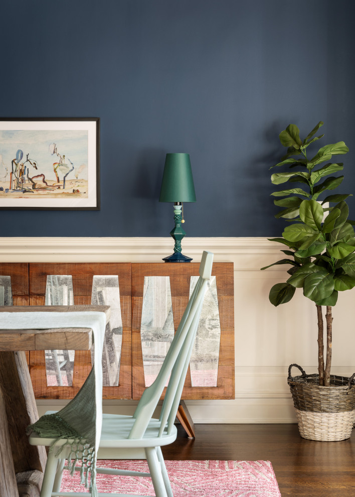 Modelo de comedor ecléctico grande con paredes azules, suelo de madera oscura, todas las chimeneas, marco de chimenea de piedra, suelo marrón, papel pintado y panelado