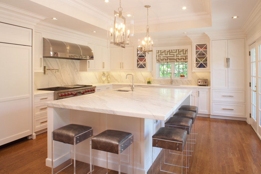 Large transitional u-shaped medium tone wood floor eat-in kitchen photo in New York with white cabinets, marble countertops, stone slab backsplash, paneled appliances, an island, an undermount sink and recessed-panel cabinets