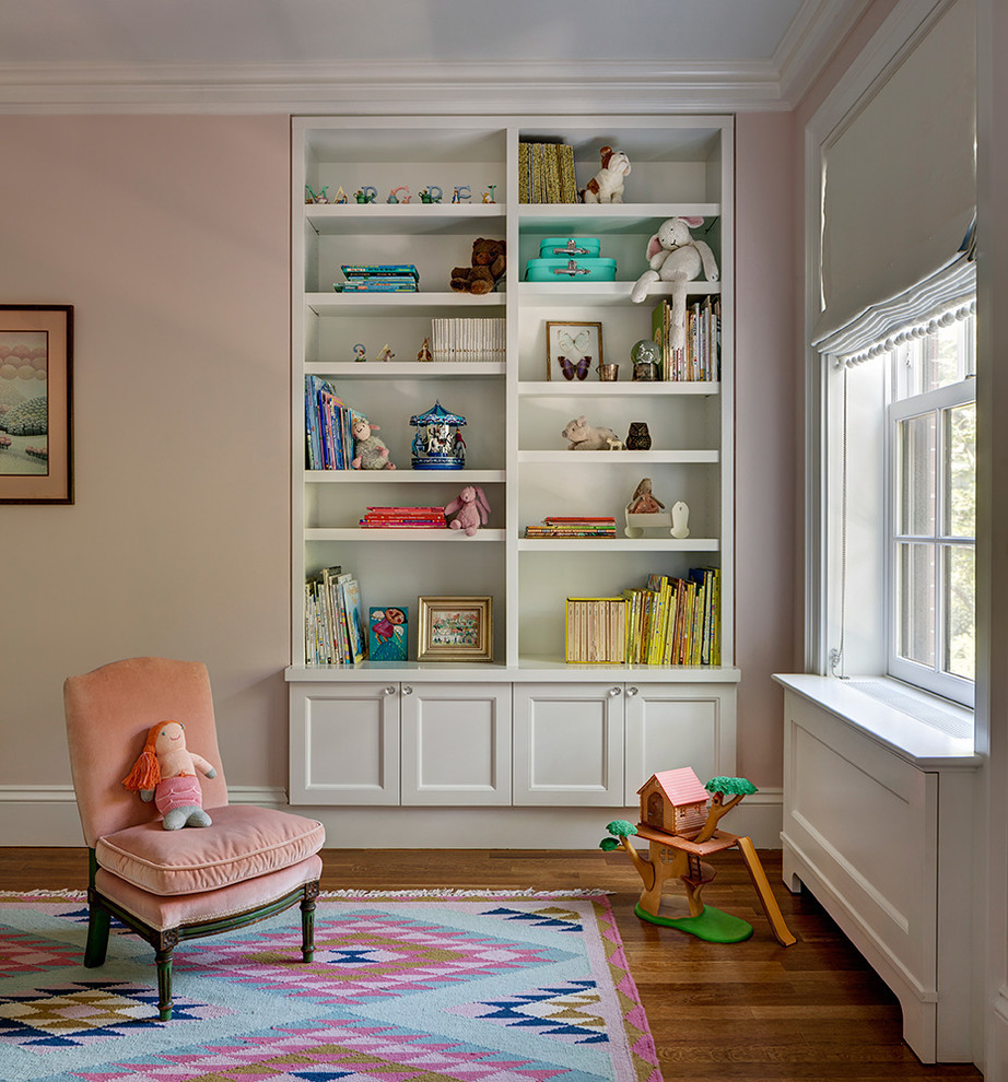 Traditional kids' room in New York with pink walls, dark hardwood floors and brown floor for girls.