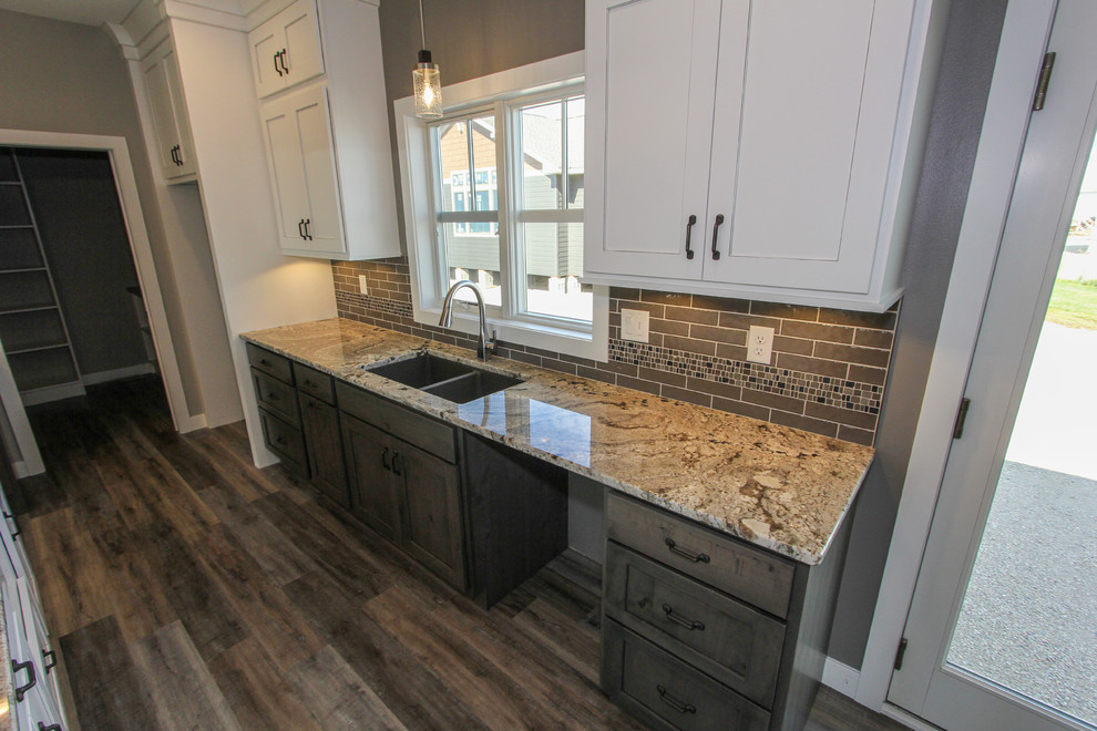 Mid-sized transitional l-shaped laminate floor and brown floor eat-in kitchen photo in Minneapolis with an undermount sink, shaker cabinets, white cabinets, granite countertops, gray backsplash, ceramic backsplash, an island and multicolored countertops