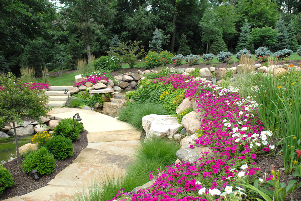 This is an example of a large traditional backyard full sun garden in Other with a garden path and natural stone pavers.