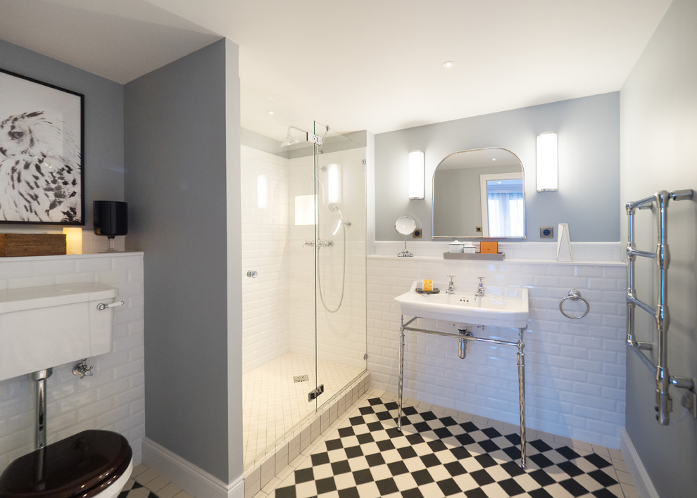 Inspiration for a traditional 3/4 bathroom in Oxfordshire with grey walls, a console sink, multi-coloured floor, a hinged shower door, a corner shower, a two-piece toilet, white tile and subway tile.