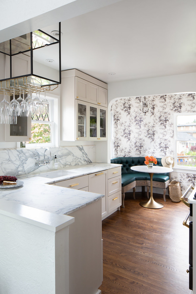 Photo of a transitional u-shaped eat-in kitchen in Seattle with an undermount sink, shaker cabinets, beige cabinets, marble benchtops, white splashback, marble splashback, panelled appliances, dark hardwood floors and a peninsula.