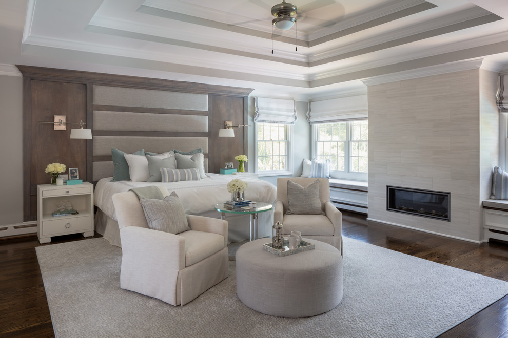 Design ideas for an expansive transitional master bedroom in New York with grey walls, medium hardwood floors, a standard fireplace, a tile fireplace surround and brown floor.
