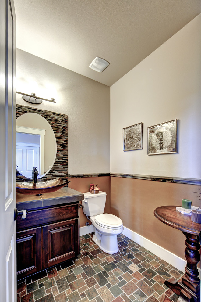 Mid-sized contemporary powder room in Seattle with raised-panel cabinets, dark wood cabinets, a two-piece toilet, beige walls, ceramic floors, a vessel sink, tile benchtops and multi-coloured floor.