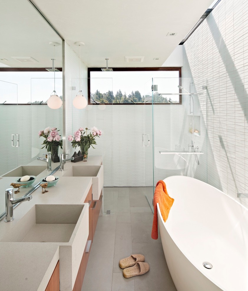Design ideas for a mid-sized midcentury master bathroom with flat-panel cabinets, brown cabinets, a freestanding tub, a curbless shower, white tile, grey walls, cement tiles, an integrated sink, engineered quartz benchtops, grey floor, a hinged shower door and beige benchtops.
