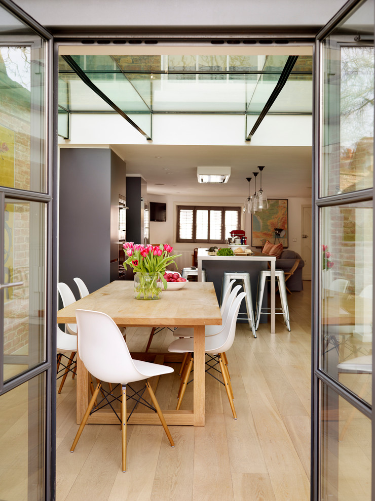 Inspiration for a large contemporary open plan dining in London with light hardwood floors.