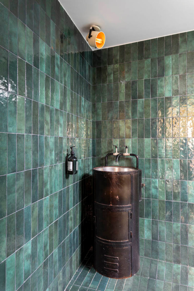 Inredning av ett mellanstort svart svart en-suite badrum, med öppna hyllor, svarta skåp, en kantlös dusch, en vägghängd toalettstol, grön kakel, keramikplattor, gröna väggar, klinkergolv i keramik, ett piedestal handfat, bänkskiva i zink, turkost golv och med dusch som är öppen