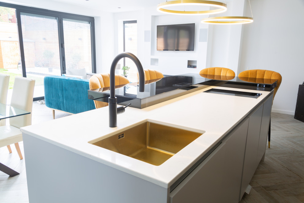 Mittelgroße Moderne Küche in L-Form mit Waschbecken, Glas-Arbeitsplatte, Kücheninsel und schwarzer Arbeitsplatte in Essex