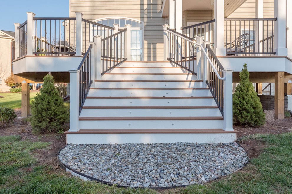 Example of a large transitional backyard deck design with a roof extension