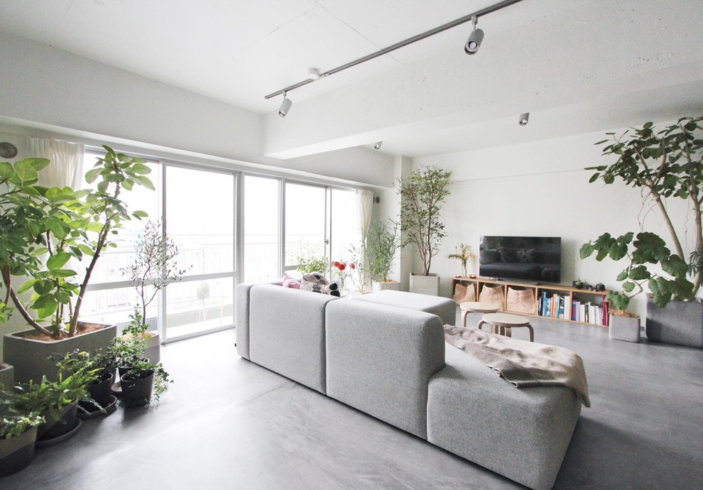 東京23区にあるインダストリアルスタイルのおしゃれなリビング (白い壁、コンクリートの床、据え置き型テレビ、グレーの床) の写真