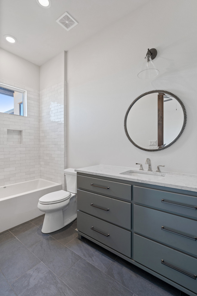 This is an example of a large country master bathroom in Dallas with furniture-like cabinets, medium wood cabinets, a drop-in tub, an open shower, a two-piece toilet, white tile, porcelain tile, white walls, travertine floors, an undermount sink, quartzite benchtops, grey floor, a shower curtain, white benchtops, a single vanity, a built-in vanity and vaulted.