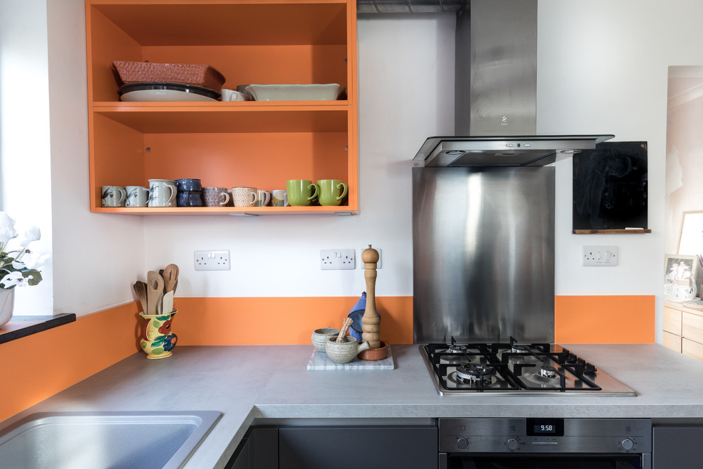 Design ideas for a mid-sized u-shaped eat-in kitchen in Hampshire with a drop-in sink, flat-panel cabinets, grey cabinets, laminate benchtops, orange splashback, stainless steel appliances and no island.