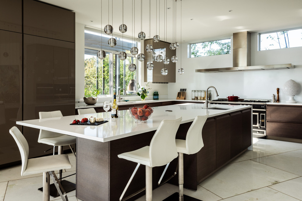 Photo of an expansive midcentury u-shaped eat-in kitchen in Seattle with an undermount sink, flat-panel cabinets, brown cabinets, quartzite benchtops, white splashback, stone slab splashback, stainless steel appliances, with island, white floor and white benchtop.