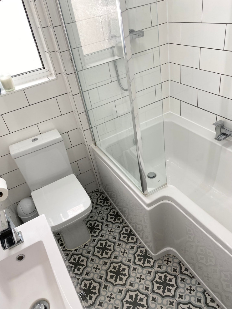 Photo of a small traditional kids bathroom in Other with flat-panel cabinets, white cabinets, a drop-in tub, a shower/bathtub combo, a one-piece toilet, white tile, ceramic tile, white walls, ceramic floors, multi-coloured floor, an open shower, white benchtops, a single vanity and a freestanding vanity.