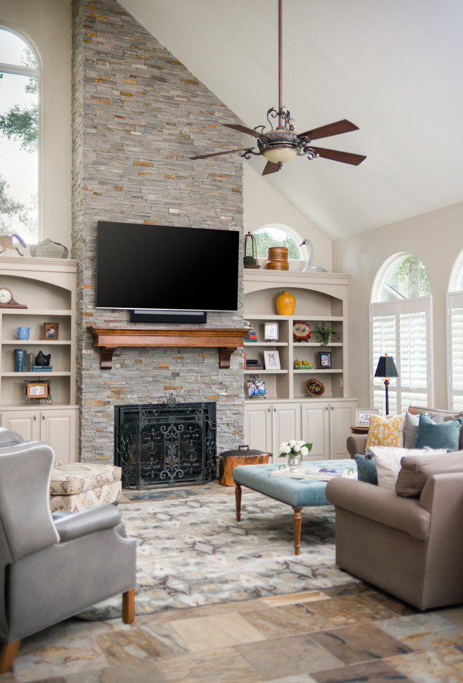Large transitional open concept family room in Houston with beige walls, slate floors, a standard fireplace, a stone fireplace surround, a wall-mounted tv and multi-coloured floor.