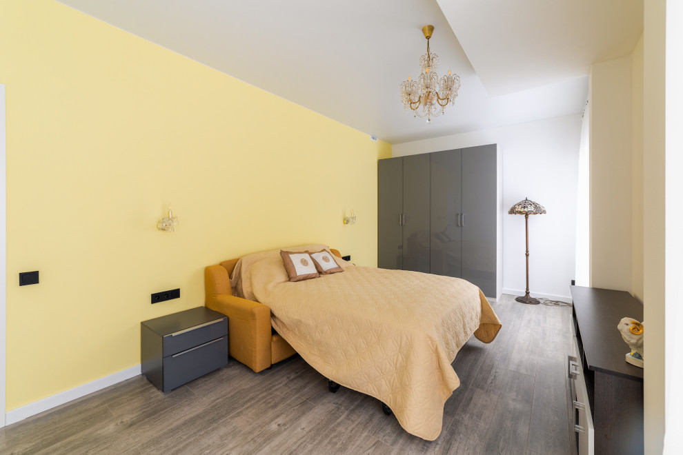 Réalisation d'une grande chambre parentale minimaliste avec un mur jaune, sol en stratifié, aucune cheminée, un sol marron et un plafond décaissé.