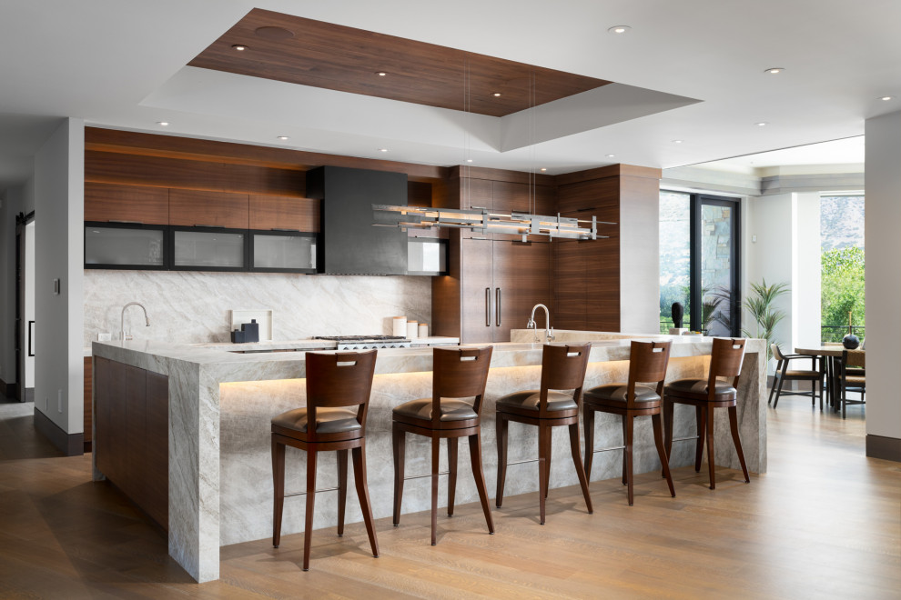 This is an example of an expansive asian single-wall open plan kitchen in Salt Lake City with an undermount sink, flat-panel cabinets, medium wood cabinets, quartzite benchtops, beige splashback, stone slab splashback, stainless steel appliances, medium hardwood floors, with island, brown floor, beige benchtop and coffered.