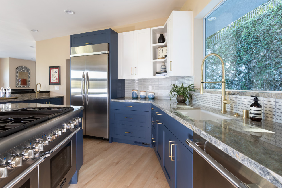 Design ideas for an expansive transitional u-shaped kitchen in Los Angeles with a single-bowl sink, shaker cabinets, blue cabinets, quartzite benchtops, white splashback, porcelain splashback, stainless steel appliances, light hardwood floors, with island and grey benchtop.