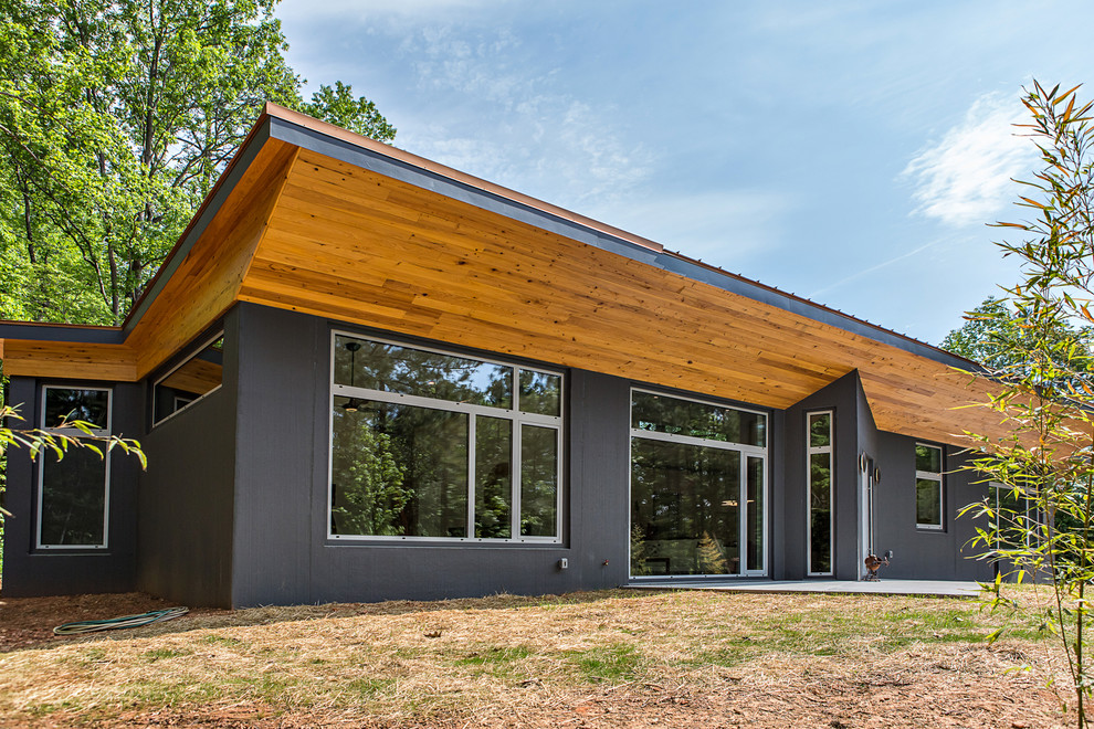 Photo of a mid-sized modern one-storey concrete grey house exterior in Raleigh with a shed roof and a metal roof.