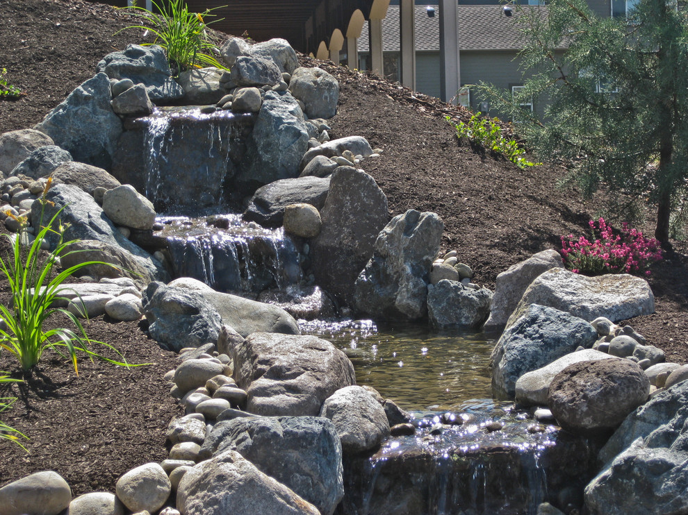 Photo of a mid-sized rustic full sun backyard stone water fountain landscape in Seattle for spring.